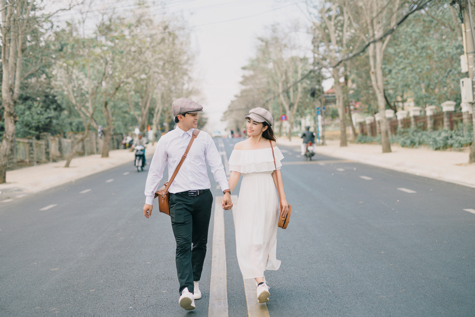 A Couple Holding Hands While Walking on a Street